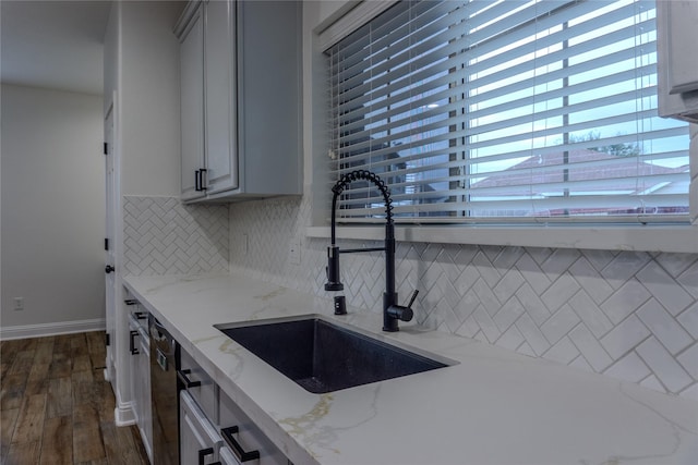 kitchen with sink, dark wood-type flooring, dishwasher, tasteful backsplash, and light stone countertops