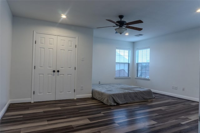 unfurnished bedroom with dark wood-type flooring, a closet, and ceiling fan