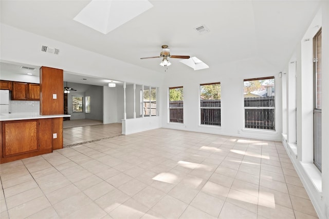 unfurnished living room with light tile patterned floors, a skylight, and ceiling fan