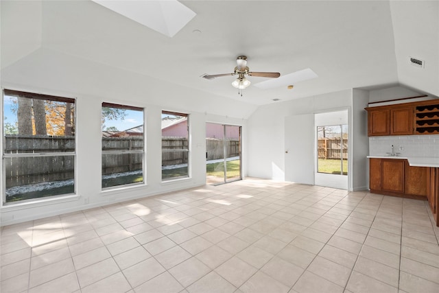 unfurnished living room featuring light tile patterned flooring, lofted ceiling with skylight, and ceiling fan