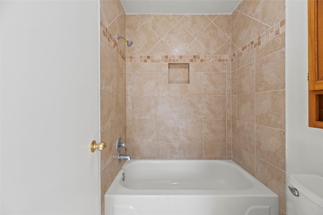 bathroom featuring tiled shower / bath and toilet