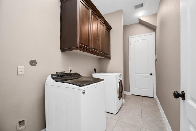 clothes washing area with light tile patterned floors, washing machine and dryer, and cabinets