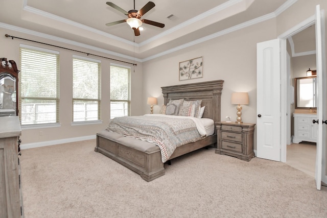 bedroom featuring a tray ceiling, light colored carpet, ceiling fan, and ensuite bathroom