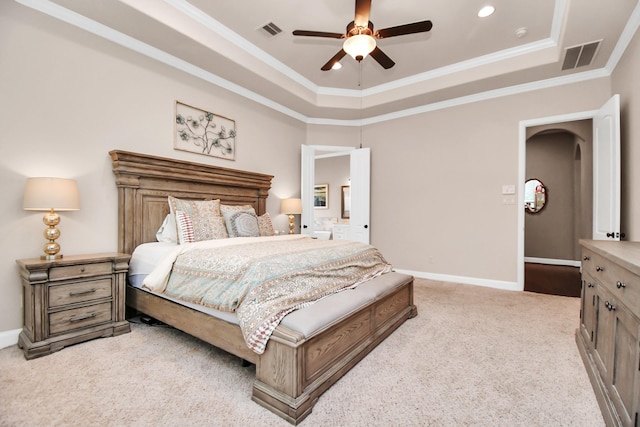 bedroom with ornamental molding, light colored carpet, a raised ceiling, and ceiling fan