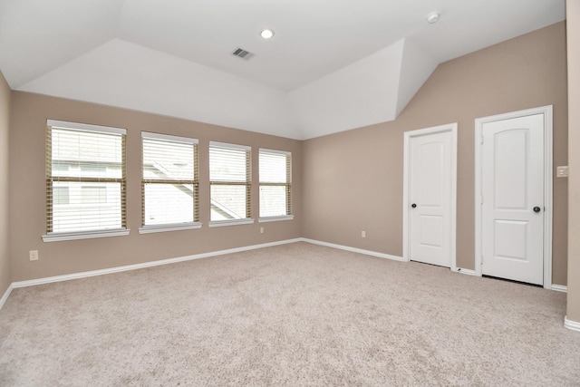 carpeted empty room with plenty of natural light and vaulted ceiling