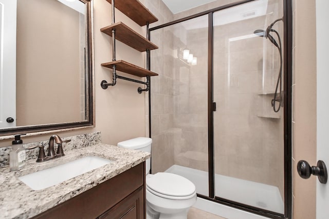 bathroom featuring vanity, a shower with shower door, and toilet