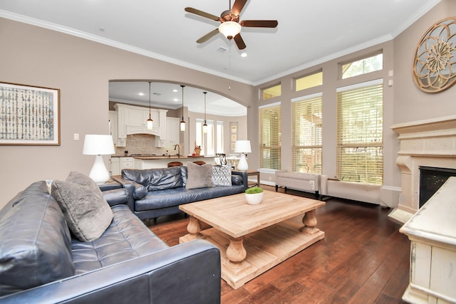 living room with dark hardwood / wood-style floors, sink, ceiling fan, a high end fireplace, and crown molding