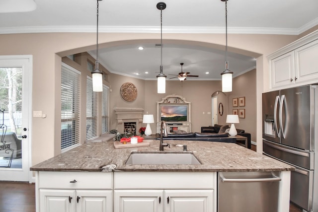 kitchen with sink, white cabinetry, hanging light fixtures, appliances with stainless steel finishes, and light stone countertops