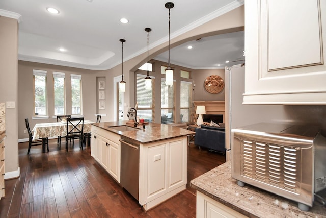 kitchen featuring sink, dishwasher, a kitchen island with sink, light stone counters, and decorative light fixtures