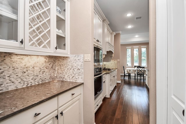 kitchen featuring stainless steel appliances, white cabinetry, dark hardwood / wood-style flooring, and decorative backsplash