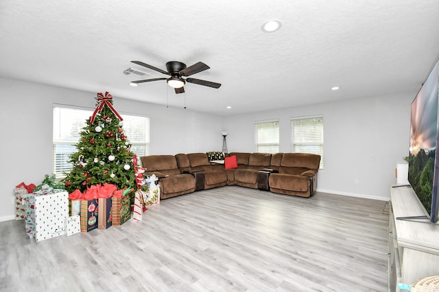 living room featuring a healthy amount of sunlight, a textured ceiling, ceiling fan, and light wood-type flooring