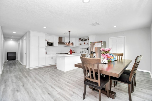 dining room with a textured ceiling and light wood-type flooring