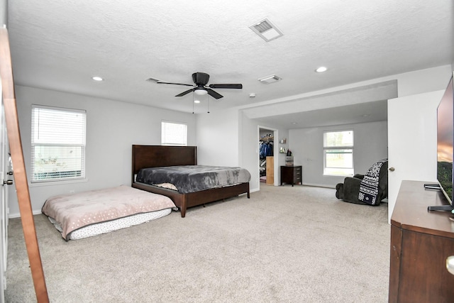 carpeted bedroom featuring a spacious closet, a textured ceiling, ceiling fan, and a closet