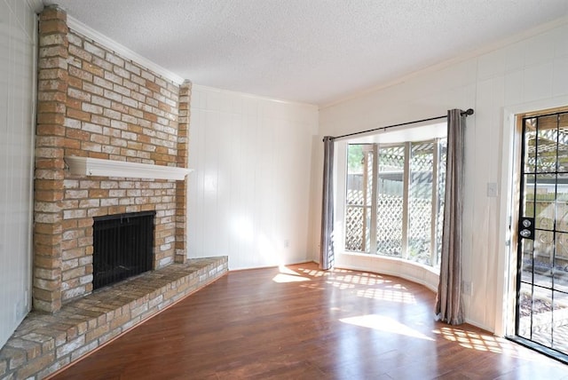 unfurnished living room with crown molding, a fireplace, a textured ceiling, and wood finished floors