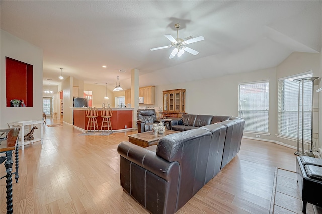 living room featuring ceiling fan, vaulted ceiling, and light wood-type flooring