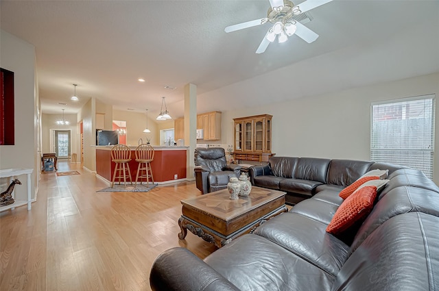 living room featuring ceiling fan with notable chandelier and light hardwood / wood-style floors