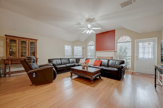 living room with light hardwood / wood-style flooring, a fireplace, vaulted ceiling, and ceiling fan