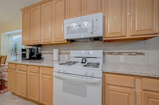 kitchen featuring light tile patterned floors, white appliances, light stone counters, light brown cabinetry, and decorative backsplash