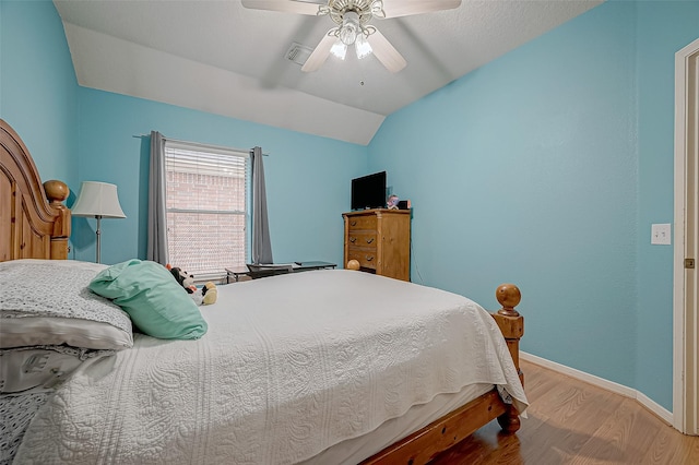 bedroom with ceiling fan, light hardwood / wood-style floors, and vaulted ceiling