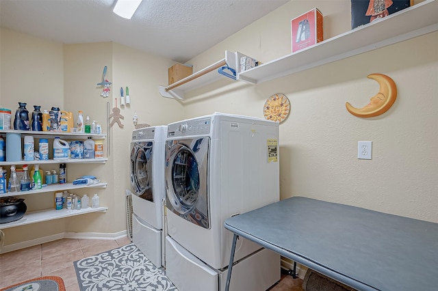 clothes washing area with washing machine and clothes dryer, a textured ceiling, and light tile patterned floors