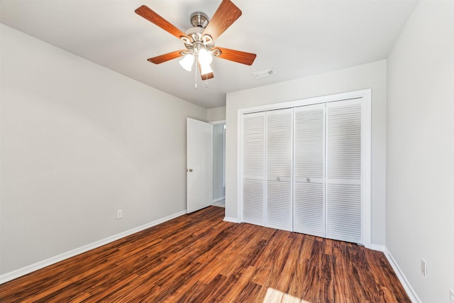 unfurnished bedroom featuring dark hardwood / wood-style flooring, ceiling fan, and a closet