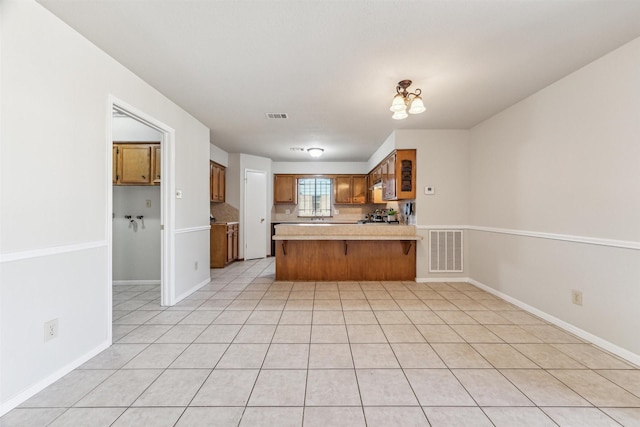 kitchen featuring tasteful backsplash, light tile patterned flooring, and kitchen peninsula