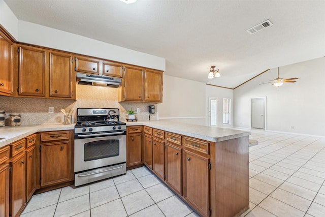 kitchen featuring lofted ceiling, gas stove, light tile patterned floors, kitchen peninsula, and backsplash