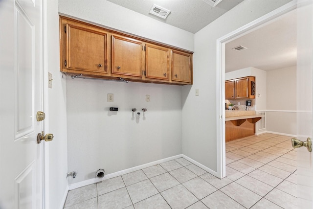 laundry room with light tile patterned flooring, cabinets, and washer hookup