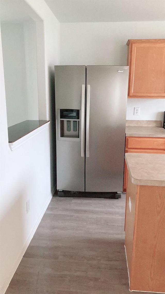 kitchen with stainless steel refrigerator with ice dispenser, light hardwood / wood-style flooring, and light brown cabinets