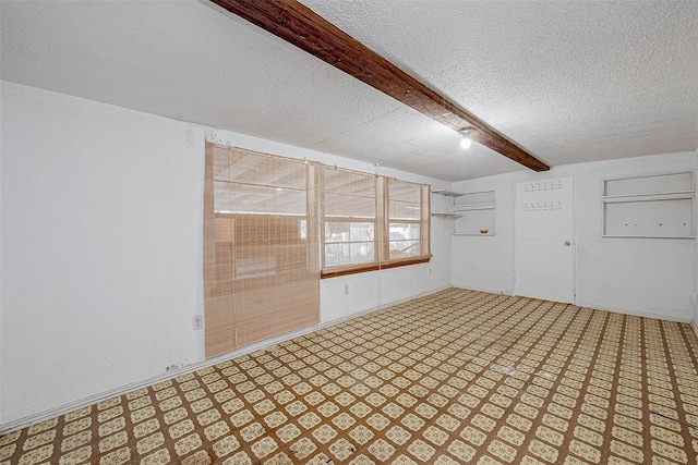 empty room with beam ceiling and a textured ceiling