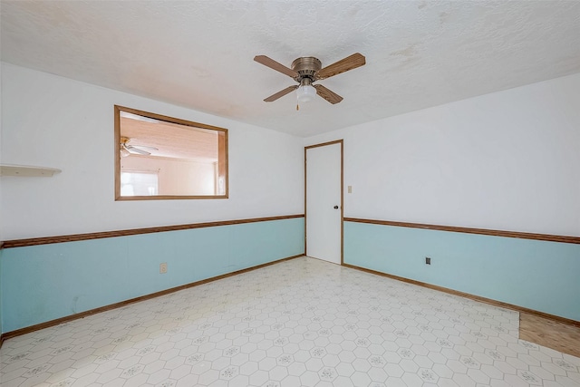 unfurnished room with ceiling fan and a textured ceiling