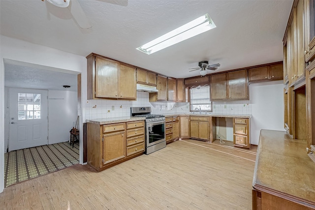 kitchen featuring light hardwood / wood-style floors, stainless steel range with gas cooktop, ceiling fan, and a skylight