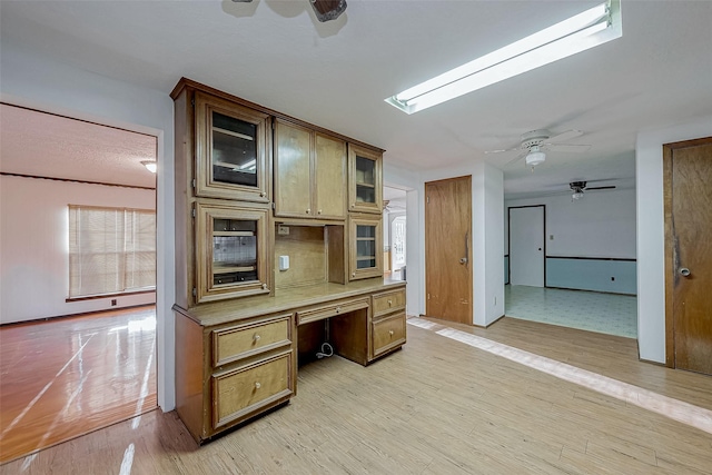 kitchen with built in desk, ceiling fan, and light wood-type flooring