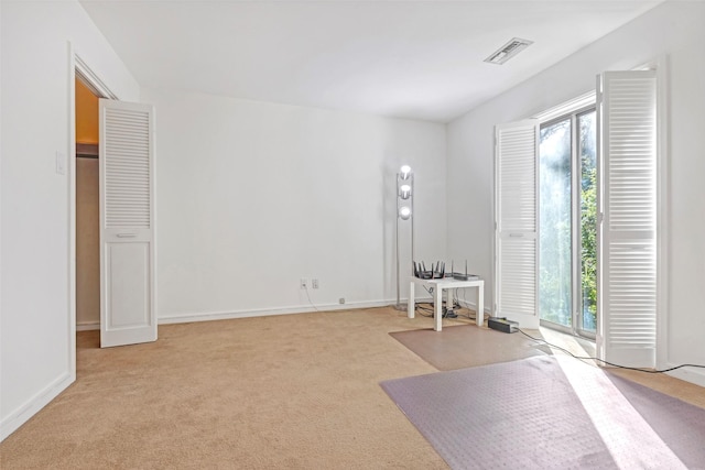 interior space featuring baseboards, visible vents, a wealth of natural light, and light colored carpet