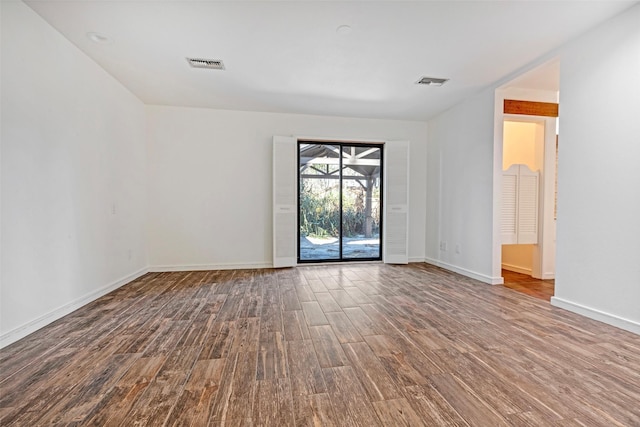 spare room with baseboards, visible vents, and wood finished floors