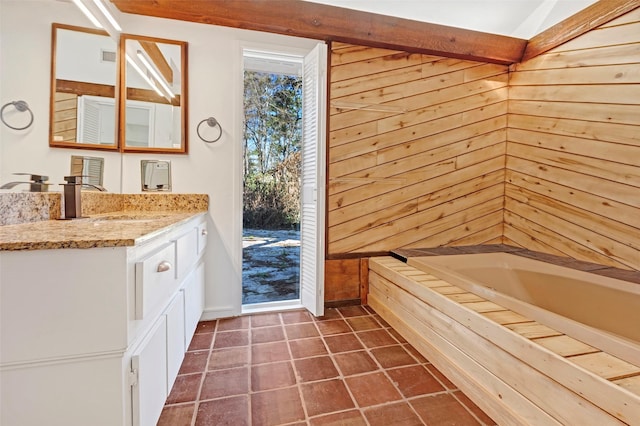 bathroom featuring vanity, tile patterned flooring, a bathtub, and wood walls