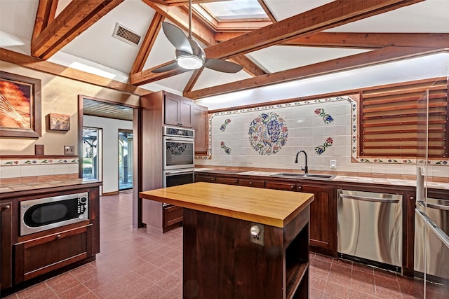 kitchen featuring visible vents, lofted ceiling with beams, butcher block countertops, appliances with stainless steel finishes, and a sink