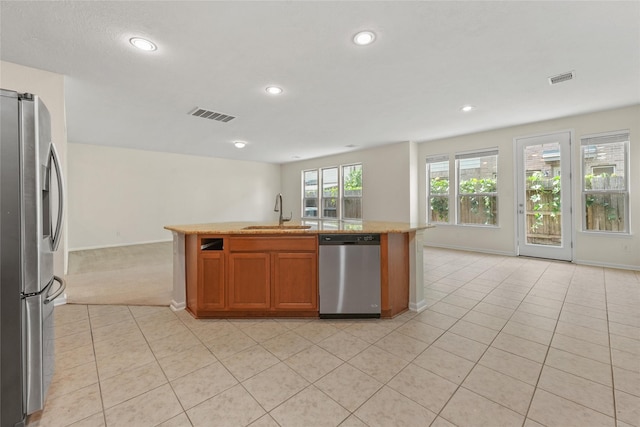 kitchen featuring stainless steel appliances, a kitchen island with sink, sink, and light tile patterned floors