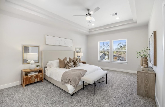 bedroom with a raised ceiling, carpet floors, and ceiling fan