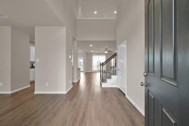 foyer entrance with a towering ceiling, wood-type flooring, and ceiling fan