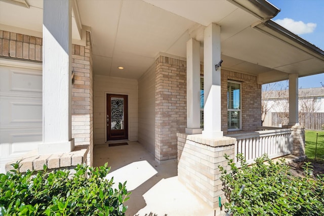 entrance to property with a porch and brick siding