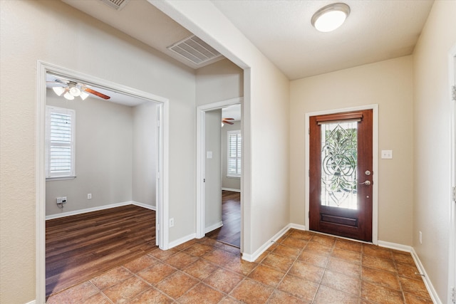 foyer featuring baseboards, visible vents, and a ceiling fan