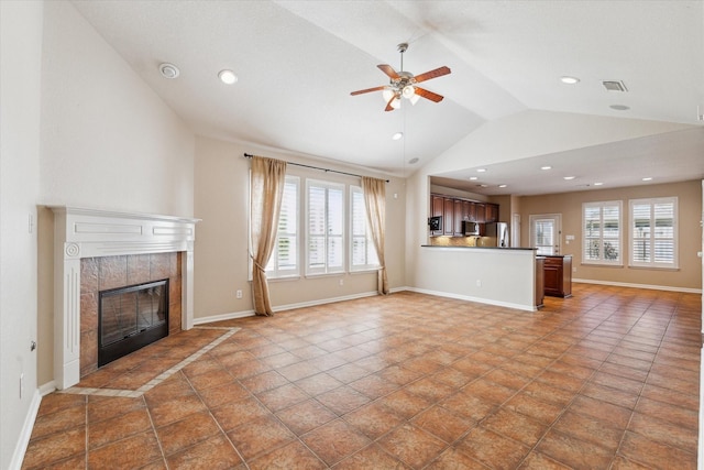 unfurnished living room featuring lofted ceiling, a healthy amount of sunlight, baseboards, and a tiled fireplace