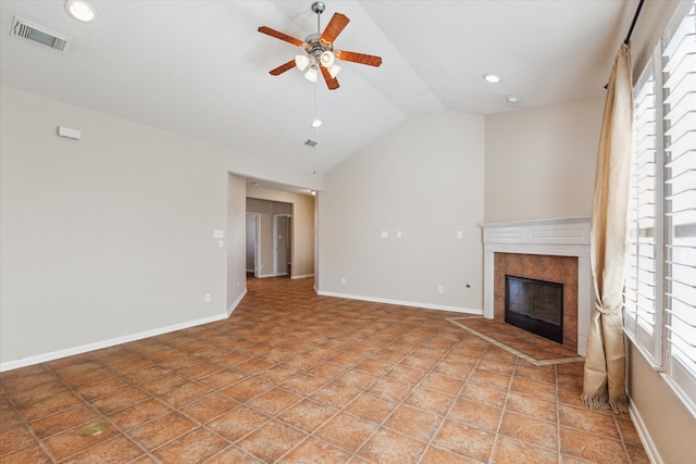 unfurnished living room with lofted ceiling, ceiling fan, a tile fireplace, visible vents, and baseboards