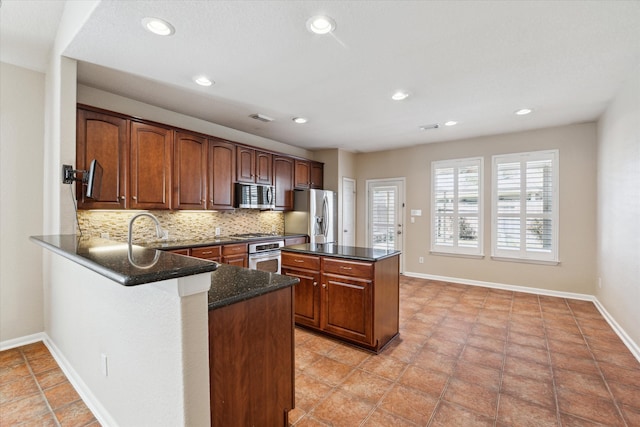 kitchen with visible vents, decorative backsplash, appliances with stainless steel finishes, a kitchen island, and baseboards