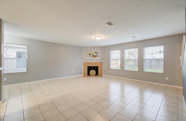 unfurnished living room featuring light tile patterned floors, a tile fireplace, and a textured ceiling