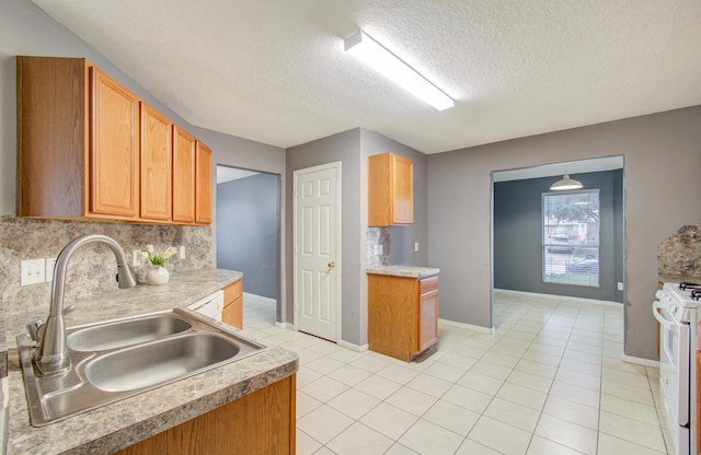 kitchen with sink, light tile patterned floors, gas range gas stove, tasteful backsplash, and a textured ceiling