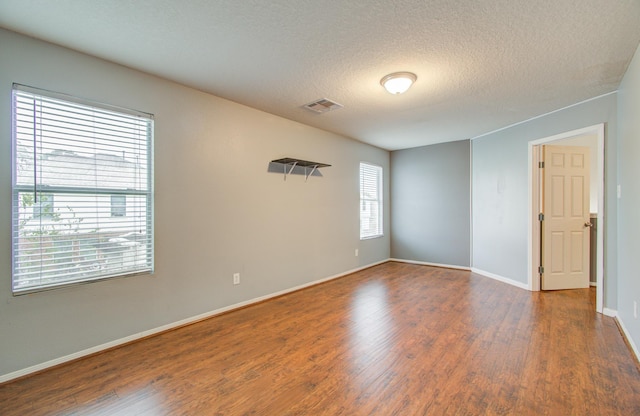 unfurnished room featuring wood-type flooring and a textured ceiling