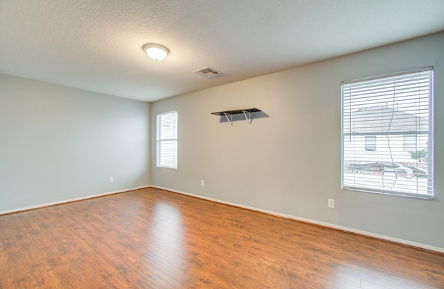 unfurnished room featuring hardwood / wood-style flooring, a healthy amount of sunlight, and a textured ceiling