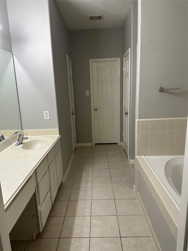 bathroom featuring tile patterned floors, visible vents, vanity, a bath, and baseboards